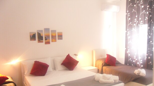 A hotel room with a bed, two bedside tables, a nightstand, and a window with curtains. - B&B Italia (Milis)