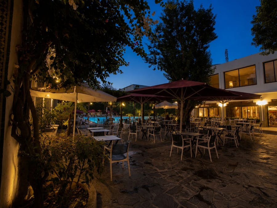 Un espace extérieur aménagé avec des tables et des chaises, une piscine et des parasols.