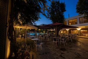 Ein Terrassenbereich im Freien mit Tischen, Stühlen, einem Pool und Sonnenschirmen.