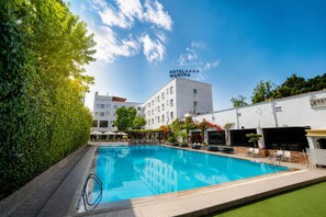 A hotel with a swimming pool, surrounded by greenery and a clear sky. - Hotel Mamora (Kenitra)