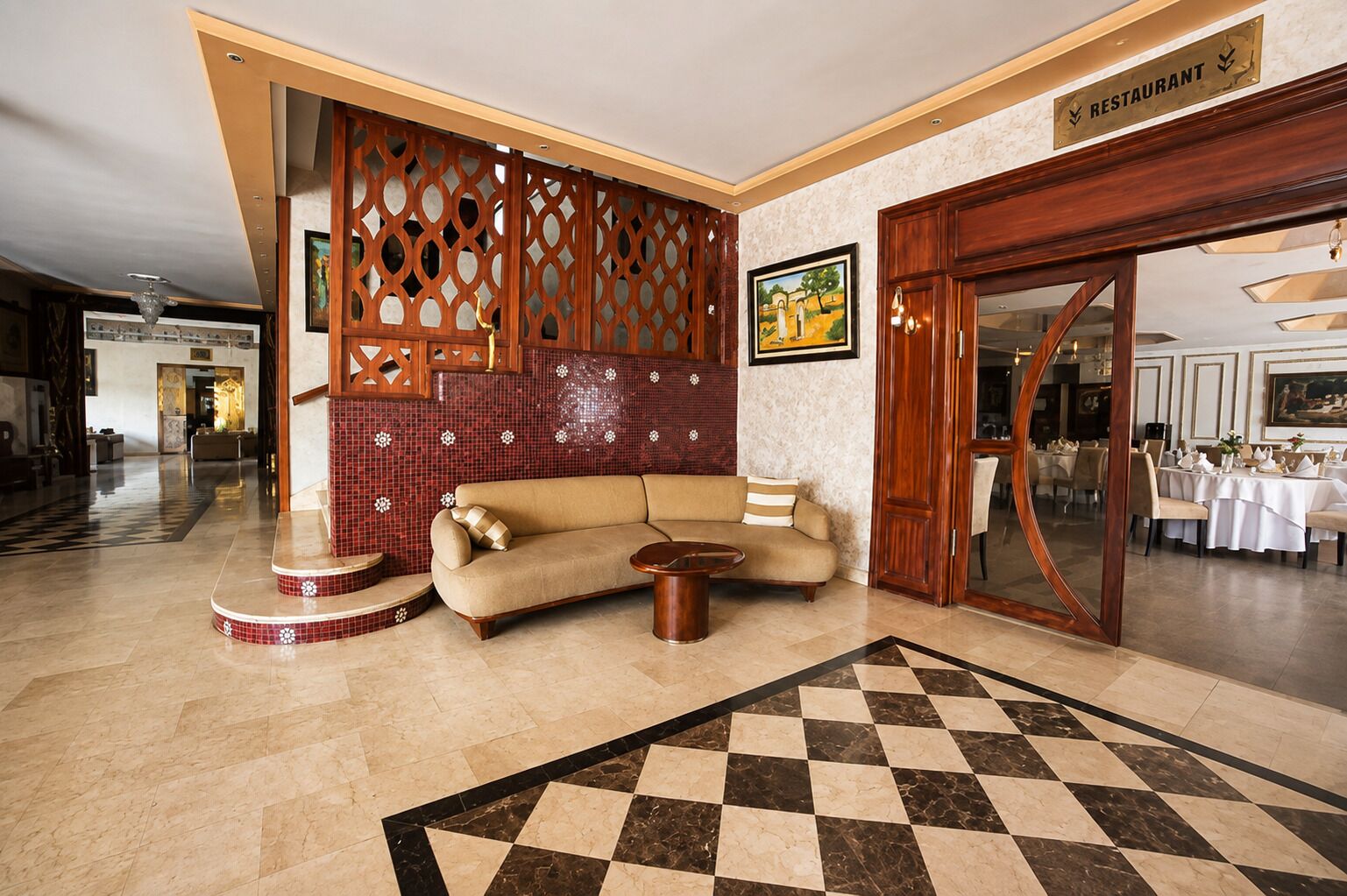 Un hall d’entrée avec un sol à carreaux, un canapé, une table basse, un mur décoratif et une enseigne de restaurant.