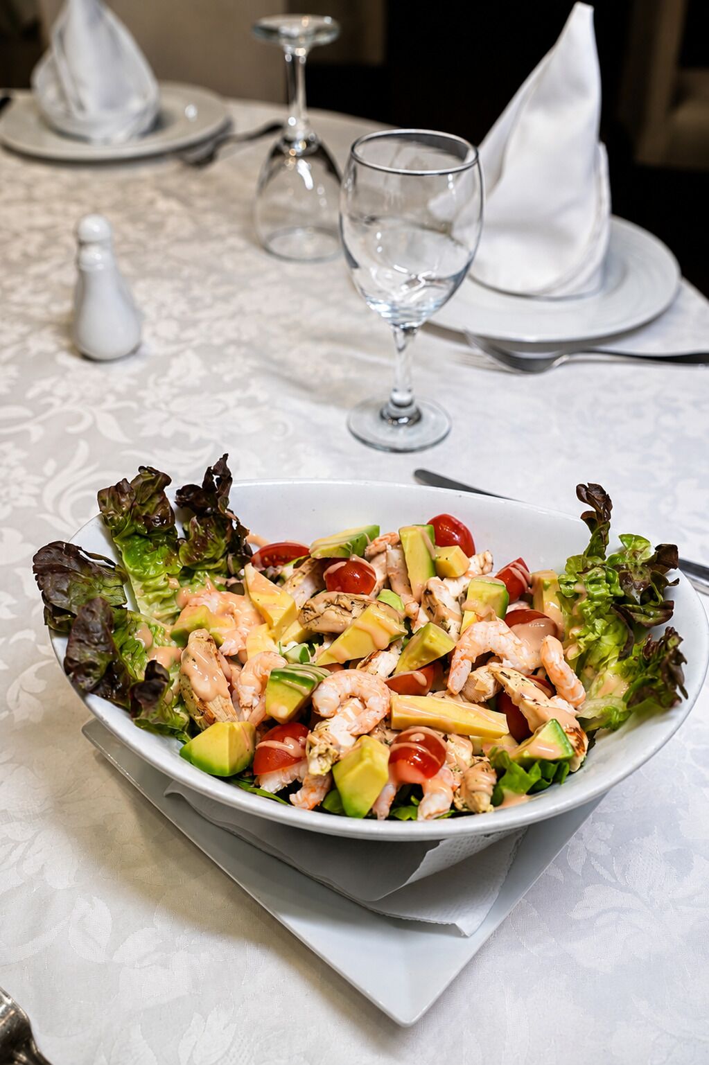 Une assiette blanche avec une salade, posée sur une nappe.