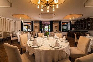 Ein Restaurant mit runden Tischen, einer Bar und Blick ins Freie.