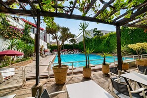 A poolside area with lounge chairs and umbrellas, surrounded by potted plants and a pergola. - Hotel Mamora (Kenitra)
