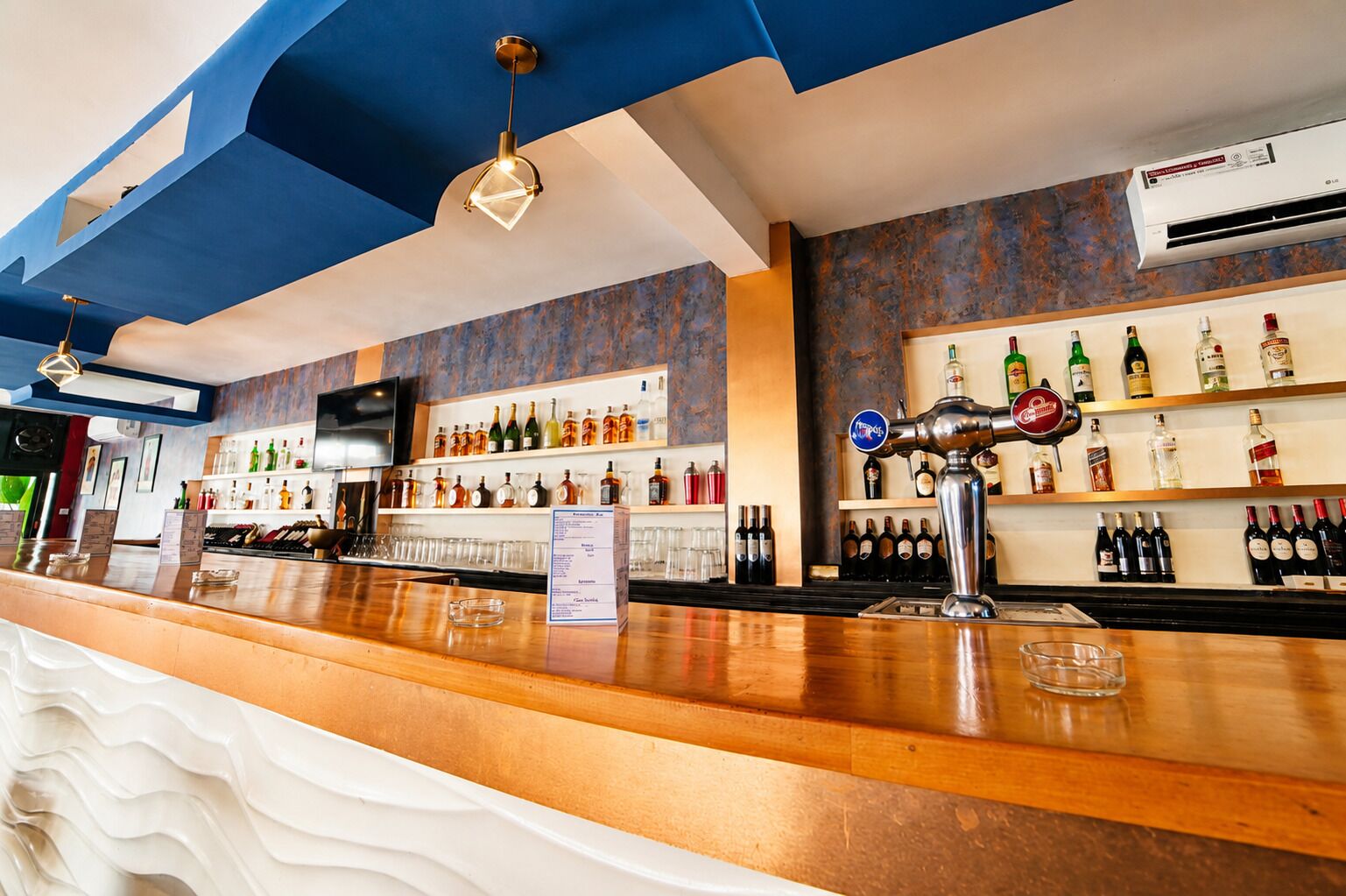A bar area with a wooden counter, shelves of liquor bottles, and a beer tap.