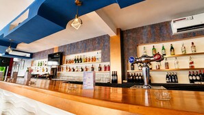 A bar area with a wooden counter, shelves of liquor bottles, and a beer tap. - Hotel Mamora (Kenitra)
