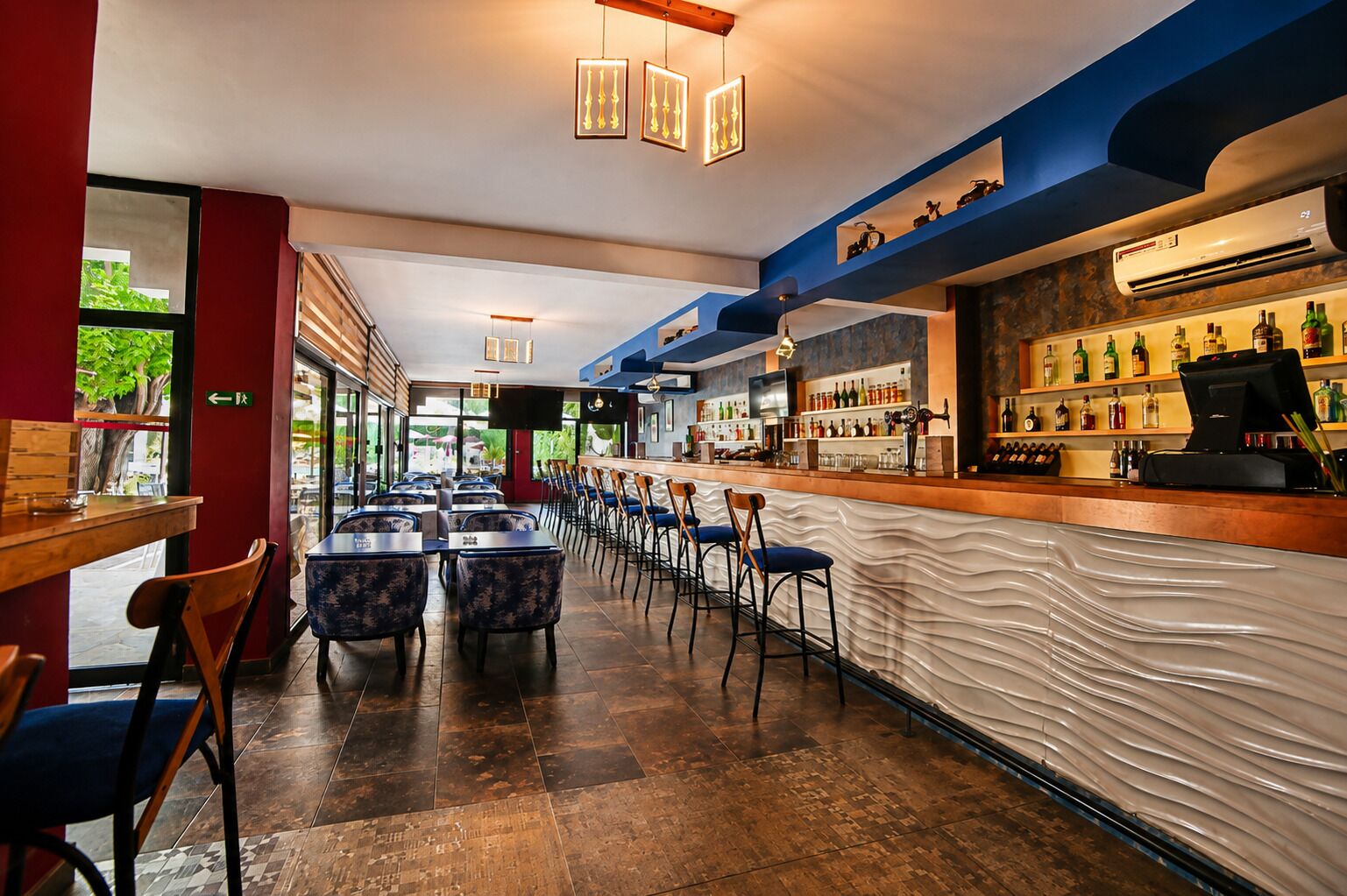 A bar area with a counter, seating, and a view of the outdoors.