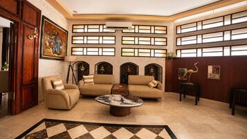 A spacious living room with a large sofa set, a coffee table, and a patterned rug.