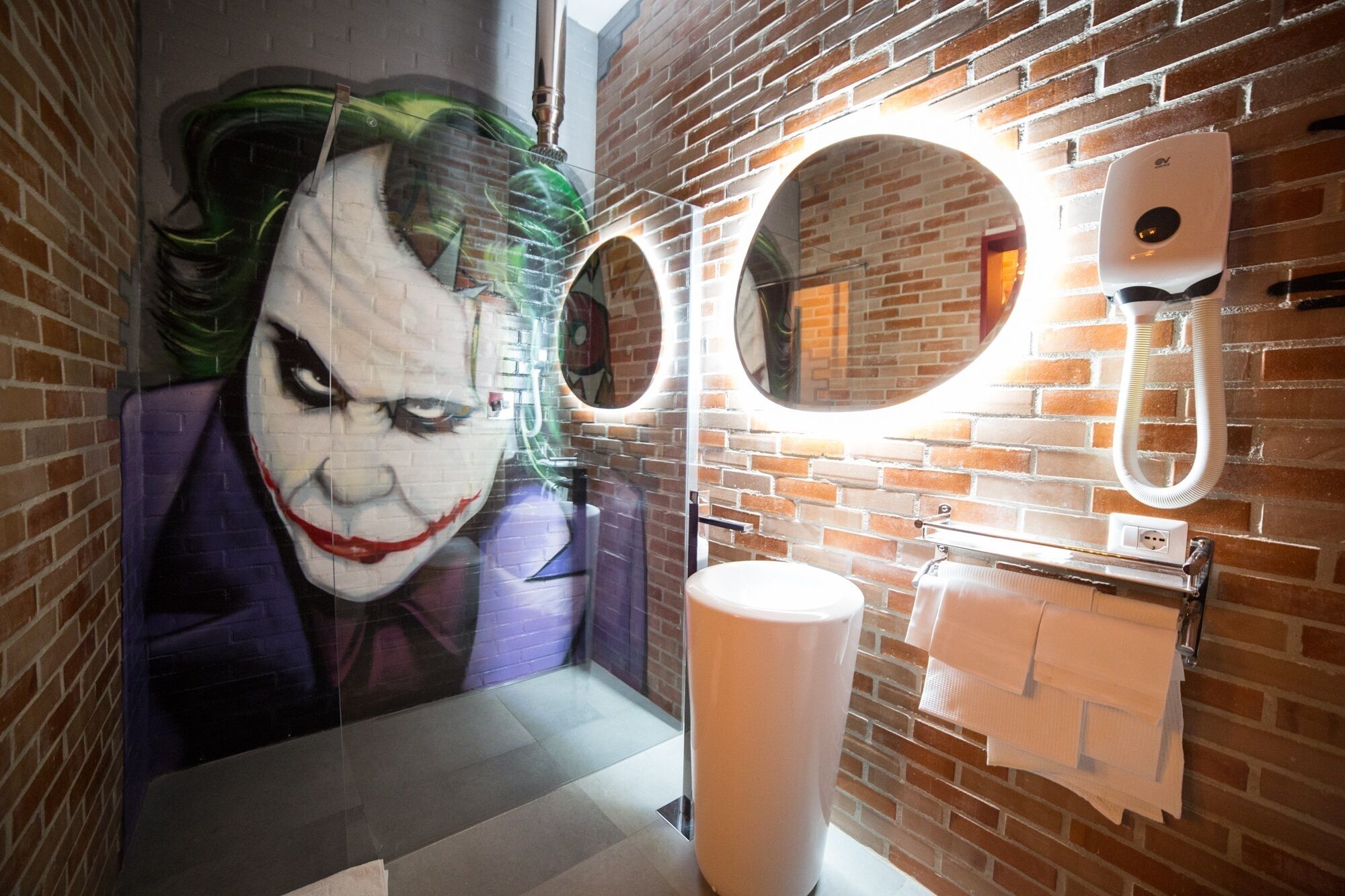 Ein Badezimmer mit Backsteinwand, einem großen Spiegel und einem Toilettenpapierhalter.