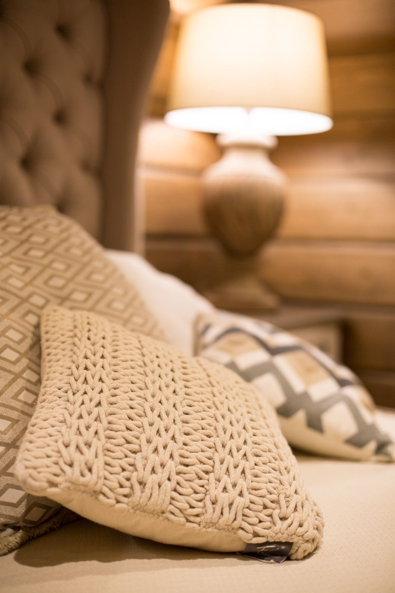 Una cama con un plaid tejido y una almohada de diseño geométrico.