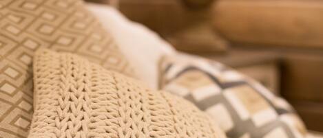 Una cama con un plaid tejido y una almohada de diseño geométrico.