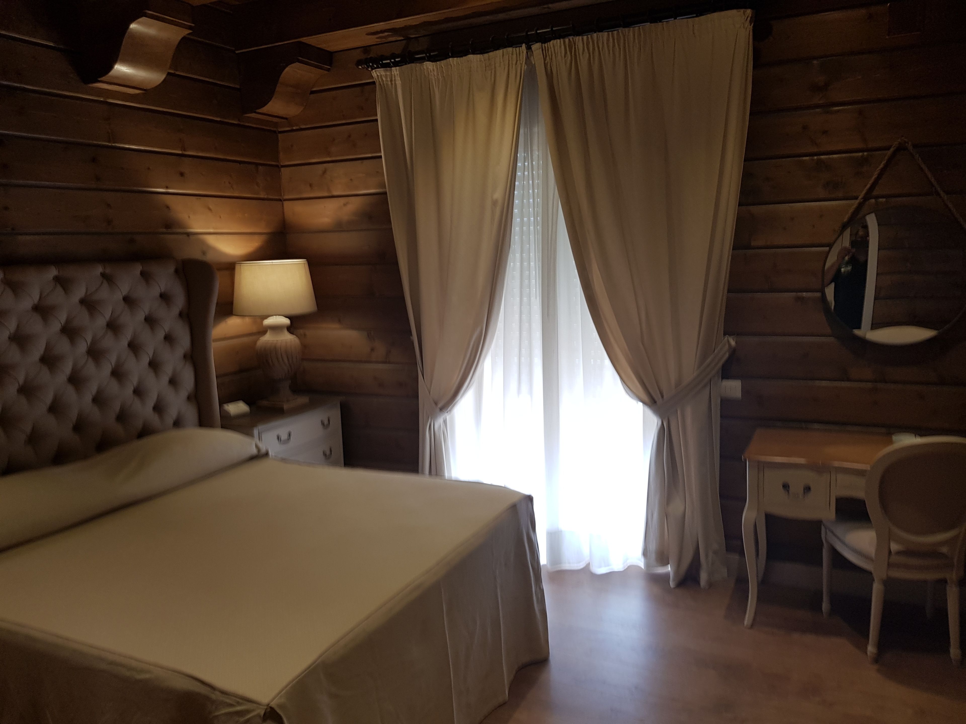 Um quarto de madeira com uma cama, uma escrivaninha e uma cadeira.