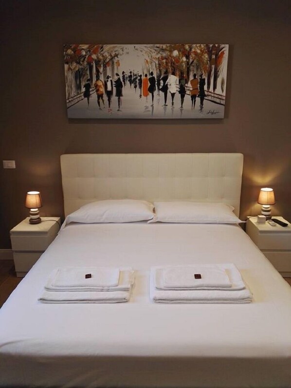 Une chambre d’hôtel avec un grand lit, deux tables de chevet et un tableau au mur.