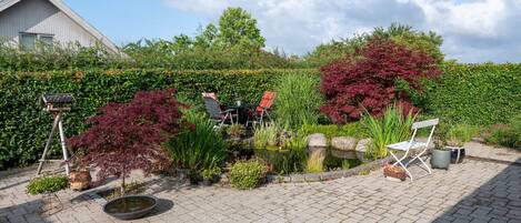 A garden with a pond, potted plants, and outdoor seating.