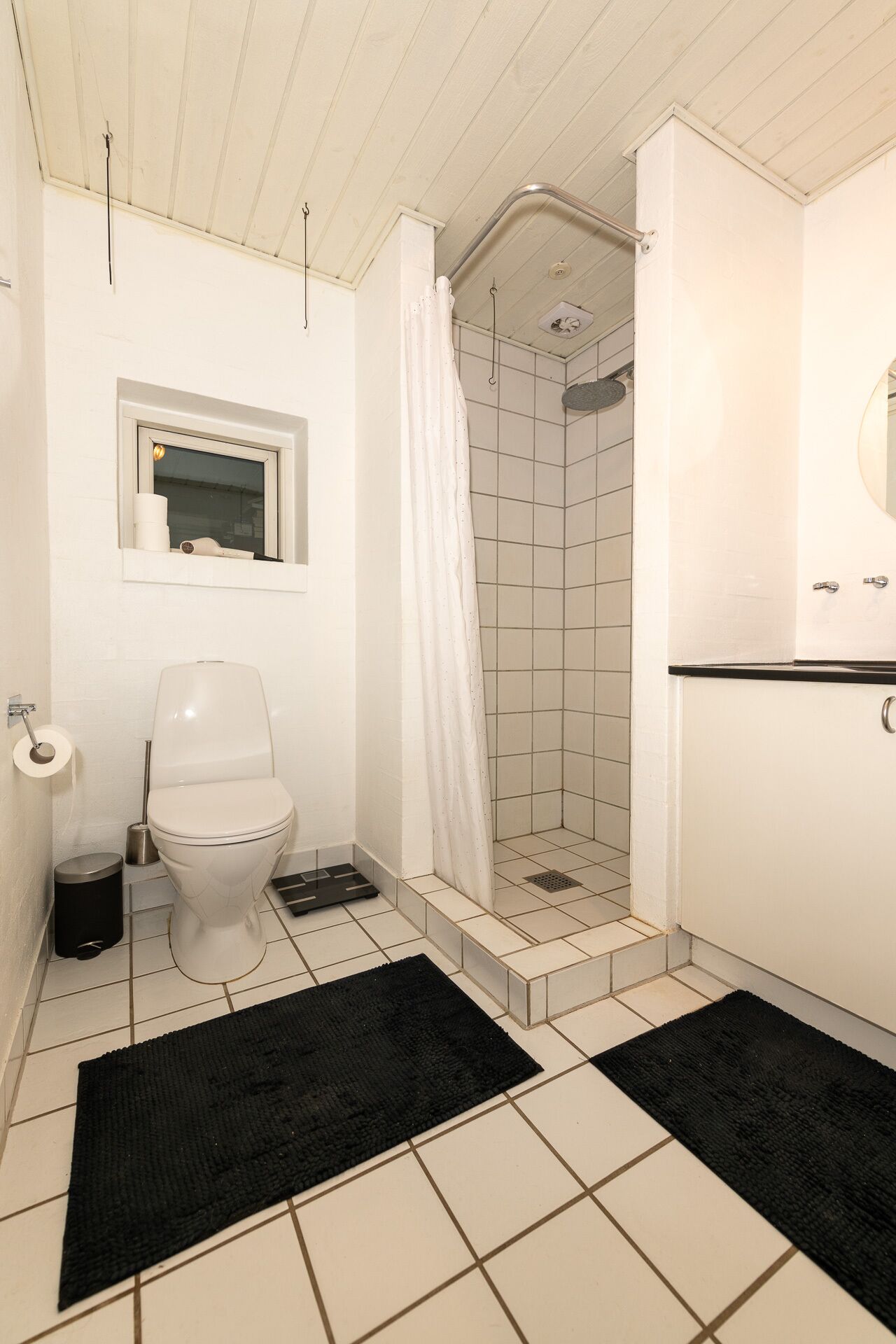 A bathroom with a toilet, a shower, and a sink.
