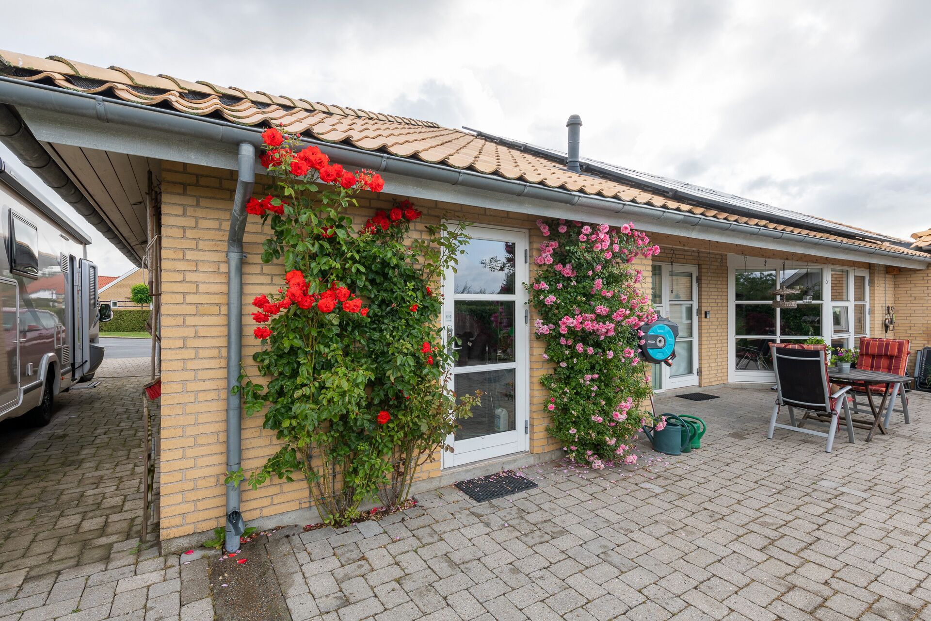 A building with a tiled roof, brick walls, and a paved entrance area.
