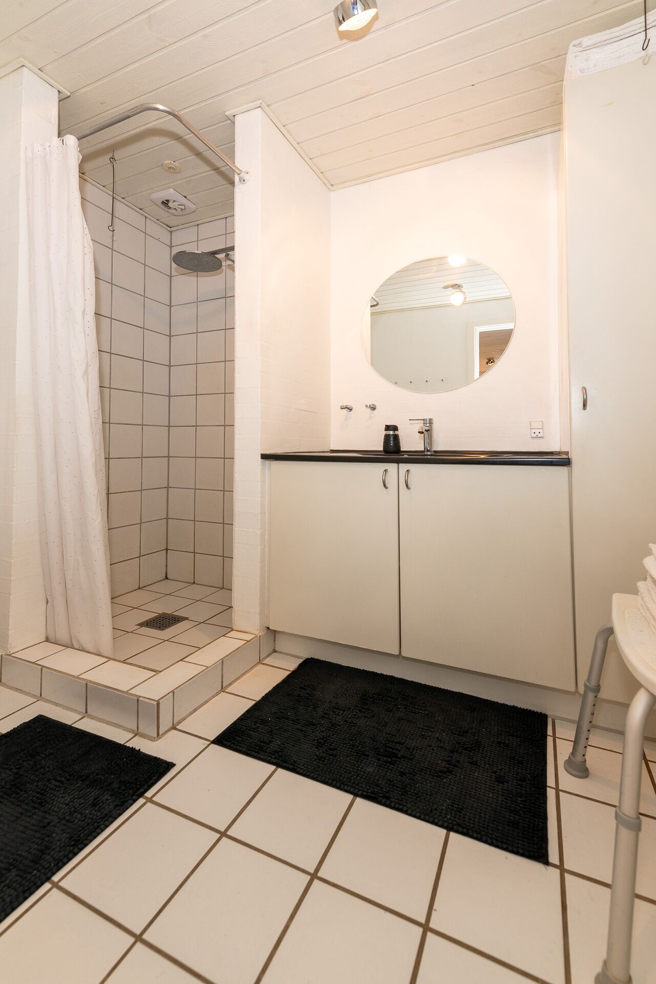 Un baño con ducha, lavabo con espejo e inodoro.