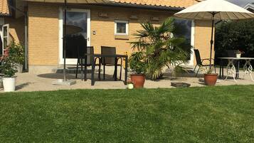 A house with a tiled roof, a patio with outdoor furniture, and a lawn.