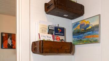 Una pared con estantes de madera que sostienen varios libros y un cuadro.