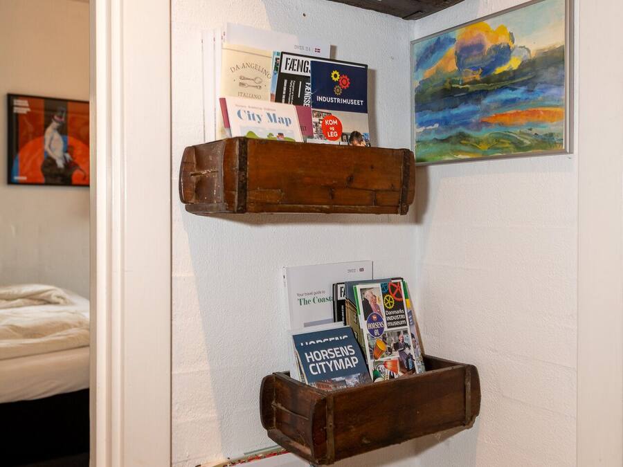 Una paret amb prestatges de fusta que contenen diversos llibres i un quadre.
