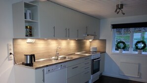 Una cocina moderna con armarios blancos, un lavamanos de acero inoxidable y un horno empotrado.
