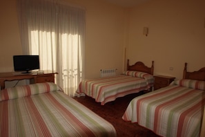 A hotel room with two single beds, a wooden desk with a television, and a window with curtains. - Hostal Sunami (La Nucia)