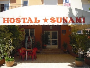 A hostel named "HOSTAL SUNAMI" with outdoor seating and potted plants. - Hostal Sunami (La Nucia)