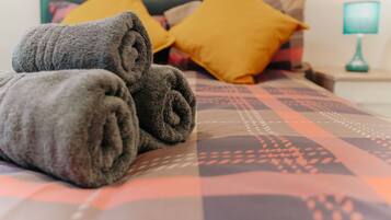 A neatly made bed with rolled towels and patterned bedding.