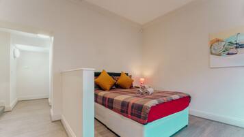A bedroom with a bed, pillows, a nightstand, and a painting on the wall.