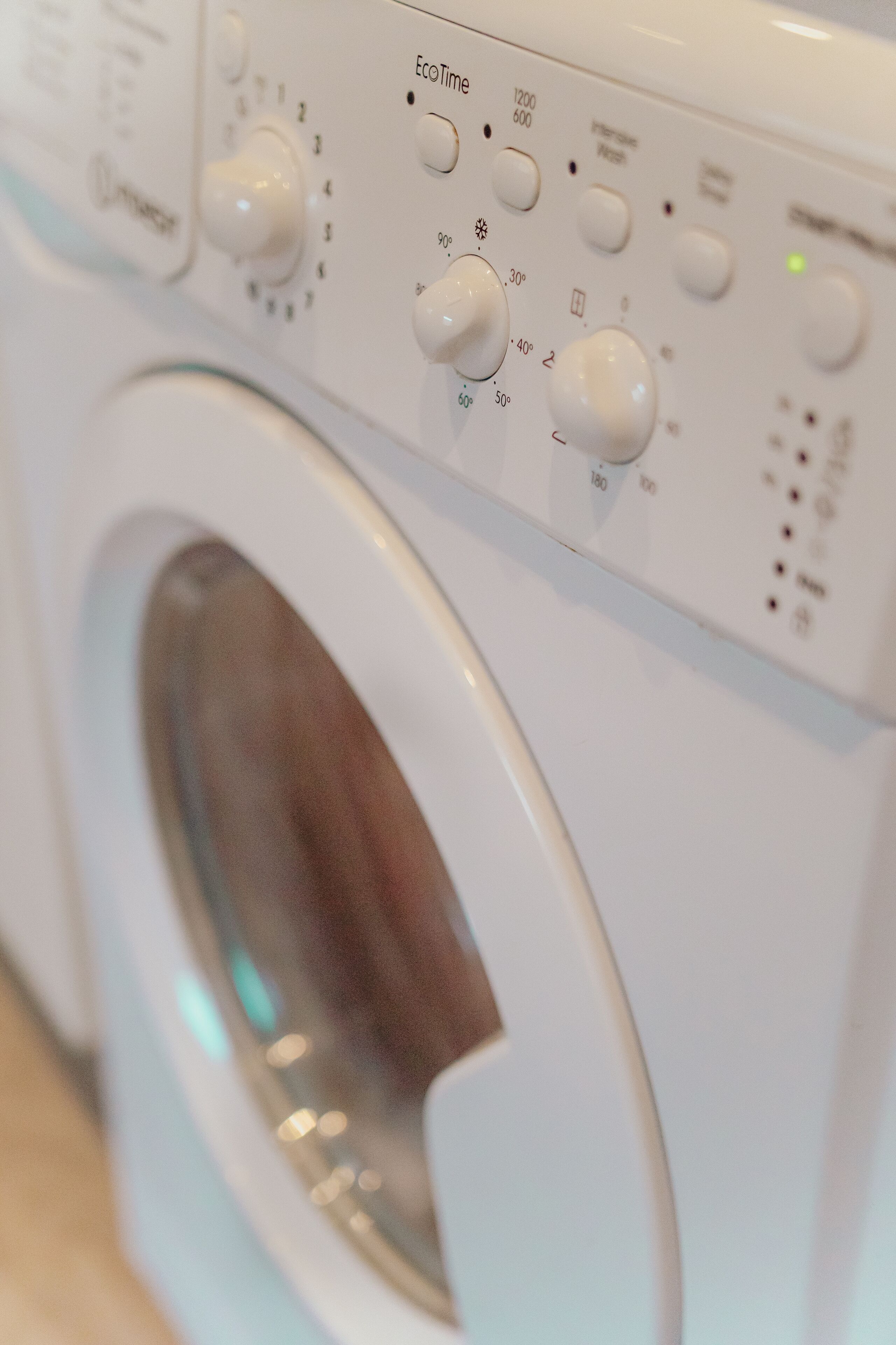 A front view of a white washing machine with control knobs and settings.