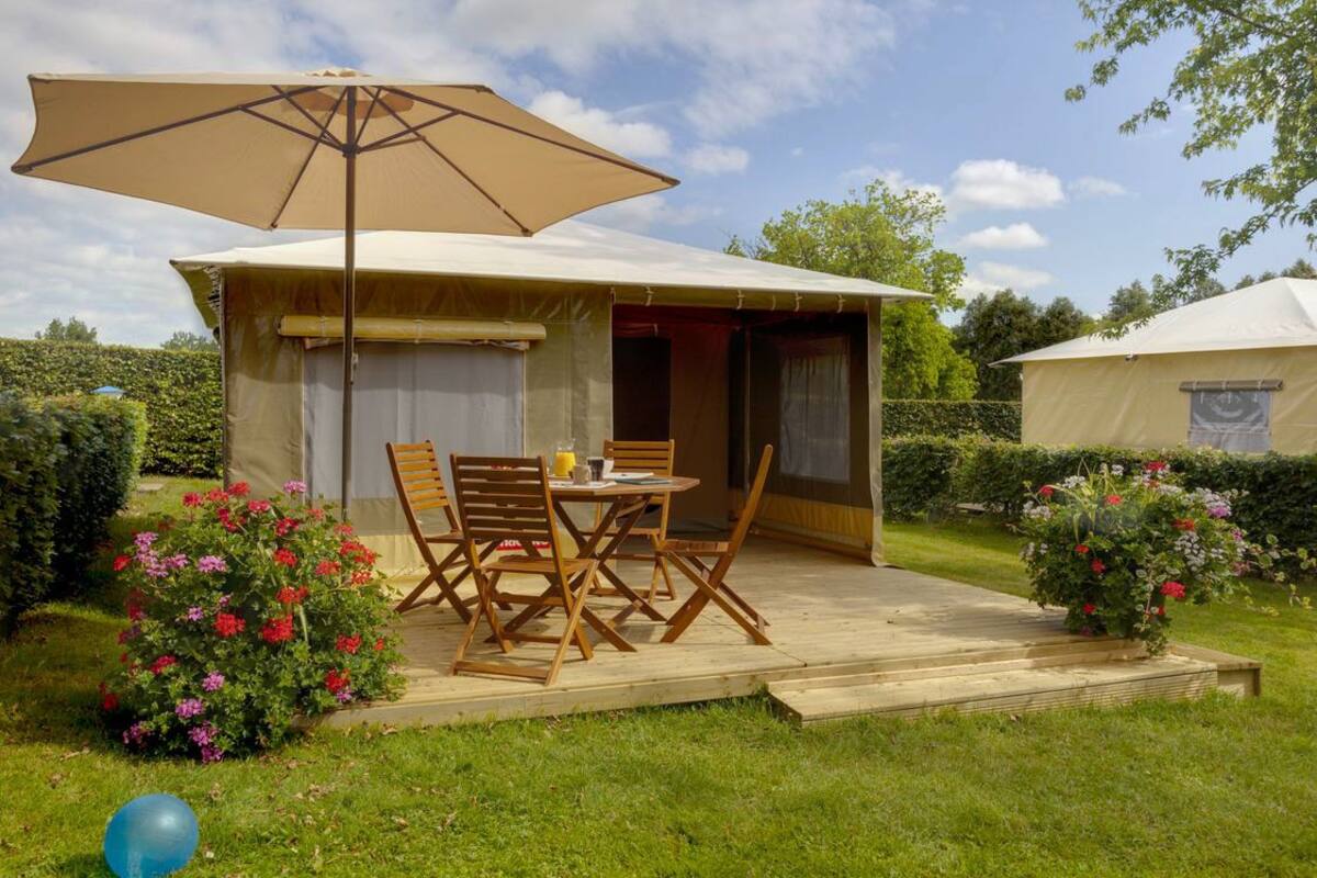 A tent with a patio area, outdoor seating, and a table with chairs.