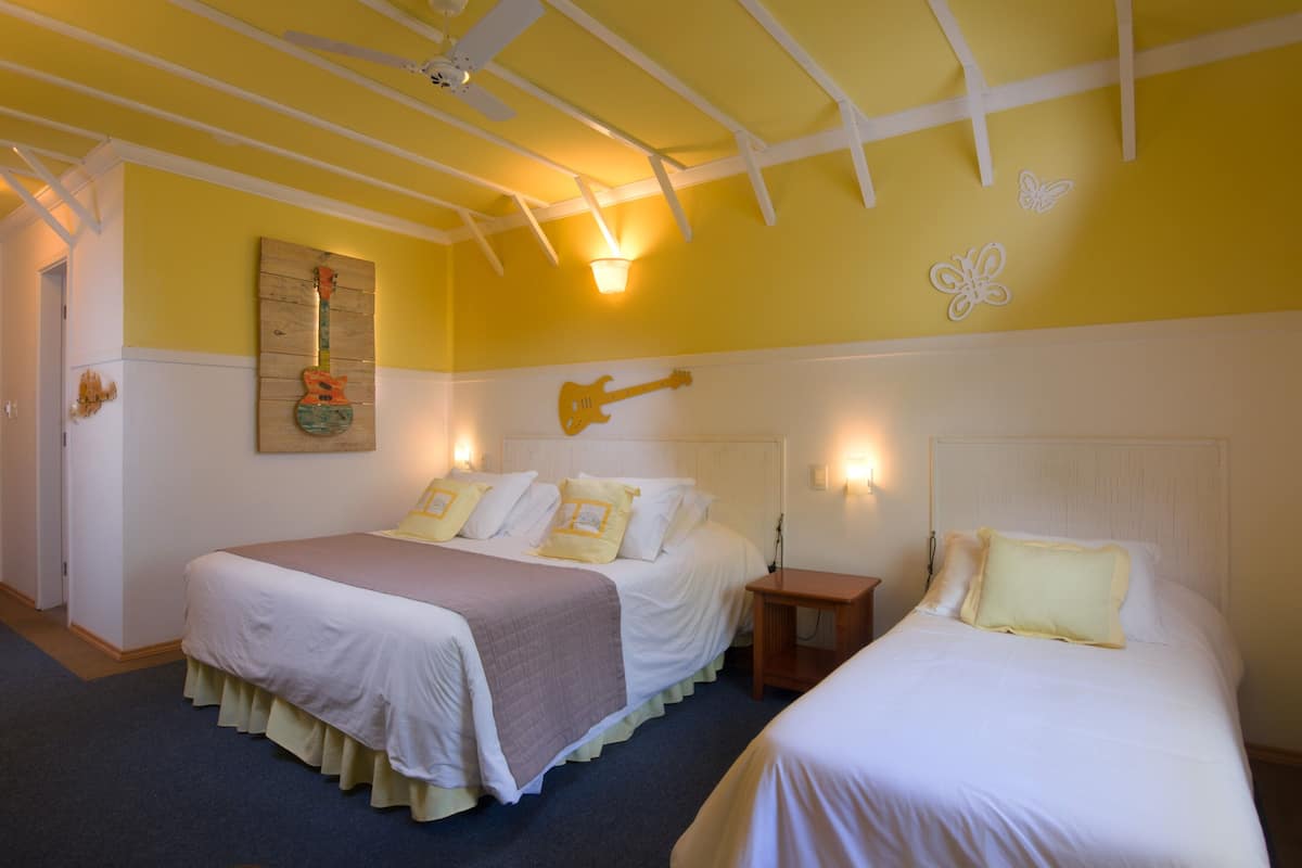 Een kamer met twee bedden, een gitaar aan de wand en een plafondventilator.
