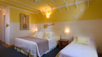 Ein Zimmer mit zwei Betten, Gitarren-Wandbild und Deckenventilator.