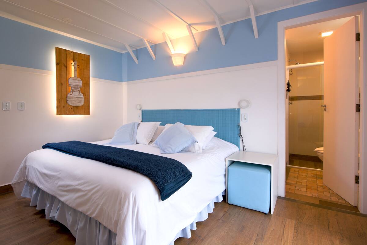 Een slaapkamer met een bed, nachtkastje en een wandlamp.