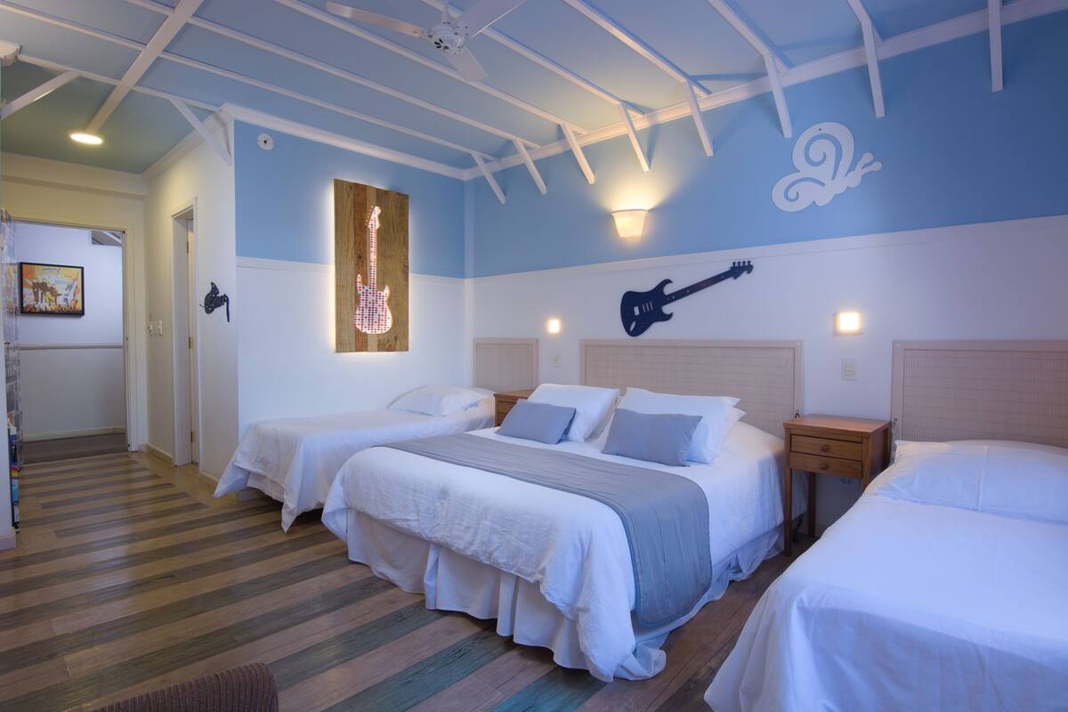 Een hotelkamer met drie bedden, houten vloeren en een plafond met zichtbare balken.