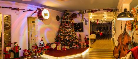 A festive room with a Christmas tree, musical instruments, and plush toys.