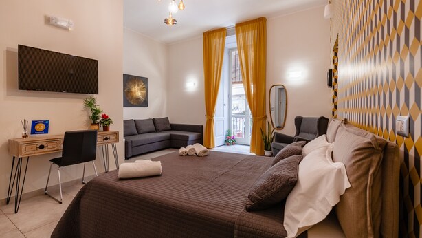 A modern bedroom with a large bed, a desk, a chair, and a TV mounted on the wall. - Monteoliveto 33 (Naples)
