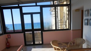 A balcony with a view of the sea, wicker furniture, and a fire extinguisher. - Terrazzino (Vibo Valentia)