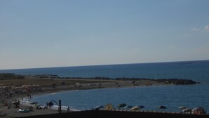A beach with umbrellas and people, a rocky shoreline, and calm water. - Terrazzino (Vibo Valentia)