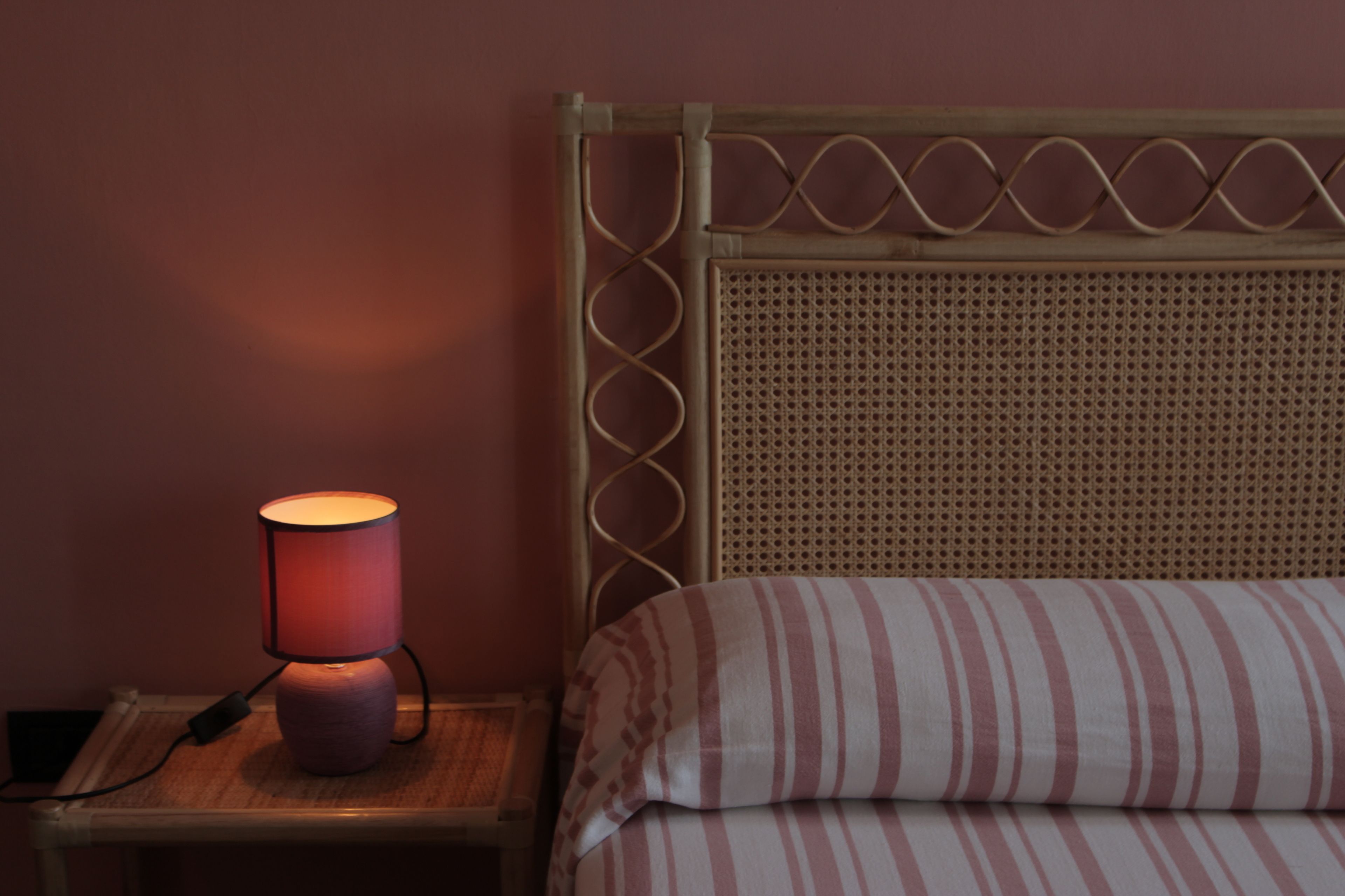 A bed with a striped pillow and a headboard with a woven design.