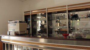 A bar area with a coffee machine, glassware, and a red bowl on the counter. - Terrazzino (Vibo Valentia)