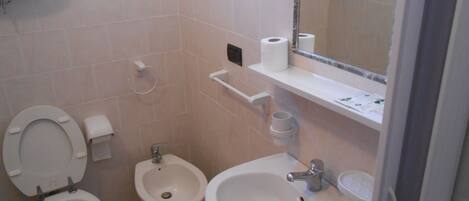 A bathroom with a toilet, bidet, and sink.