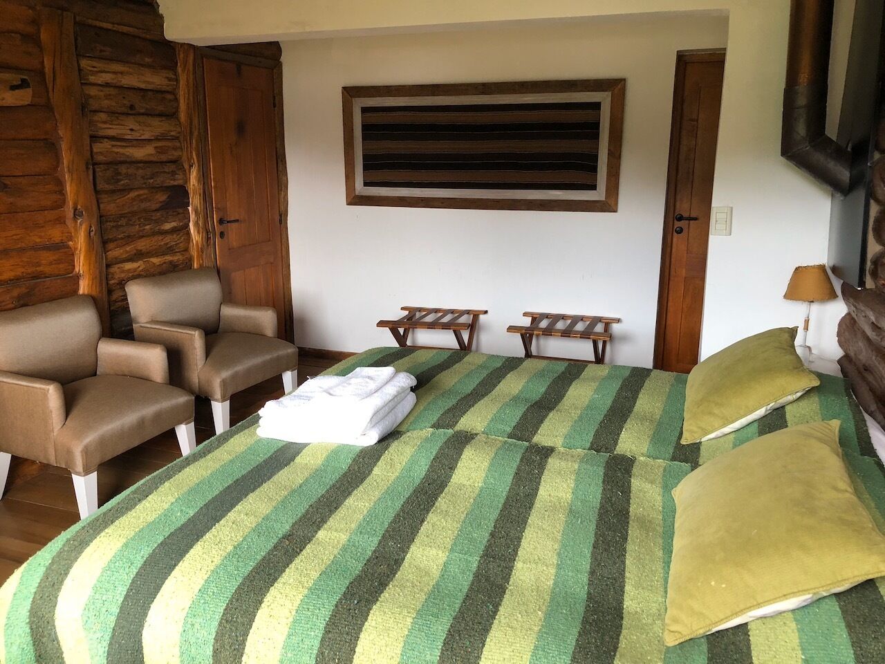A room with a bed, two chairs, a small table, and a window.