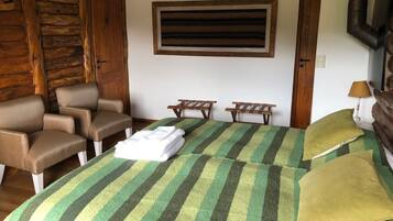 A room with a bed, two chairs, a small table, and a window.