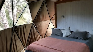 Une pièce aménagée avec une tente, un lit, des oreillers et une fenêtre.