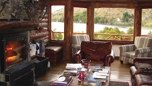 L’intérieur chaleureux d’un chalet avec une cheminée, des meubles en bois et une vue sur un lac.
