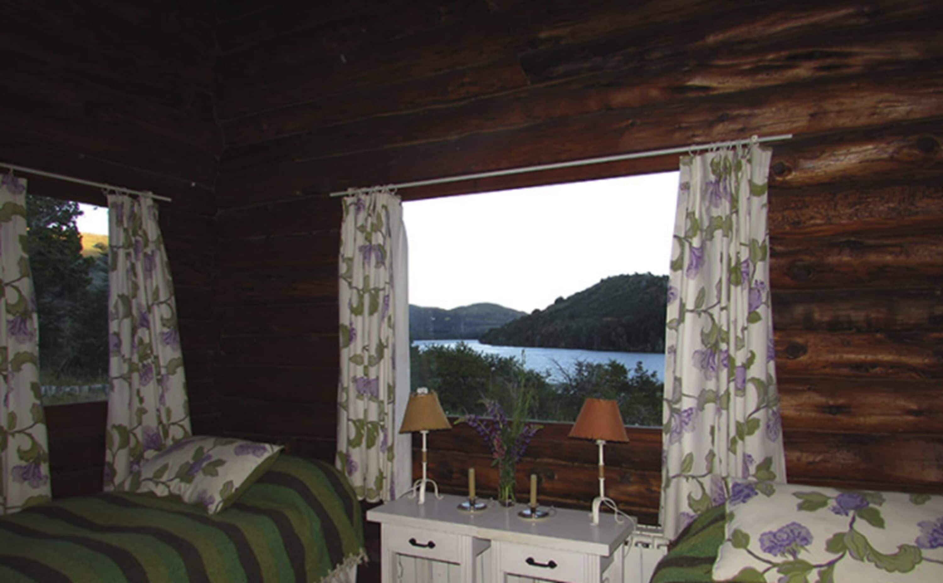 Une chambre de cabine comprenant un lit, une petite commode et une fenêtre avec des rideaux.