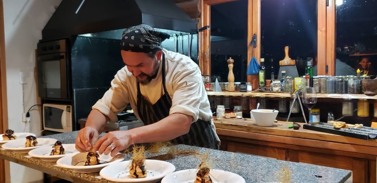 Un chef preparando comida en una cocina con mostrador, horno y varios utensilios.
