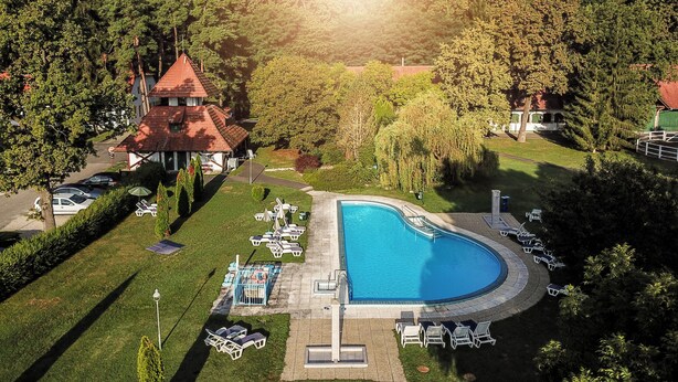 A swimming pool with lounge chairs, a gazebo, and a forested area. - Abbázia Country Club (Márokföld)