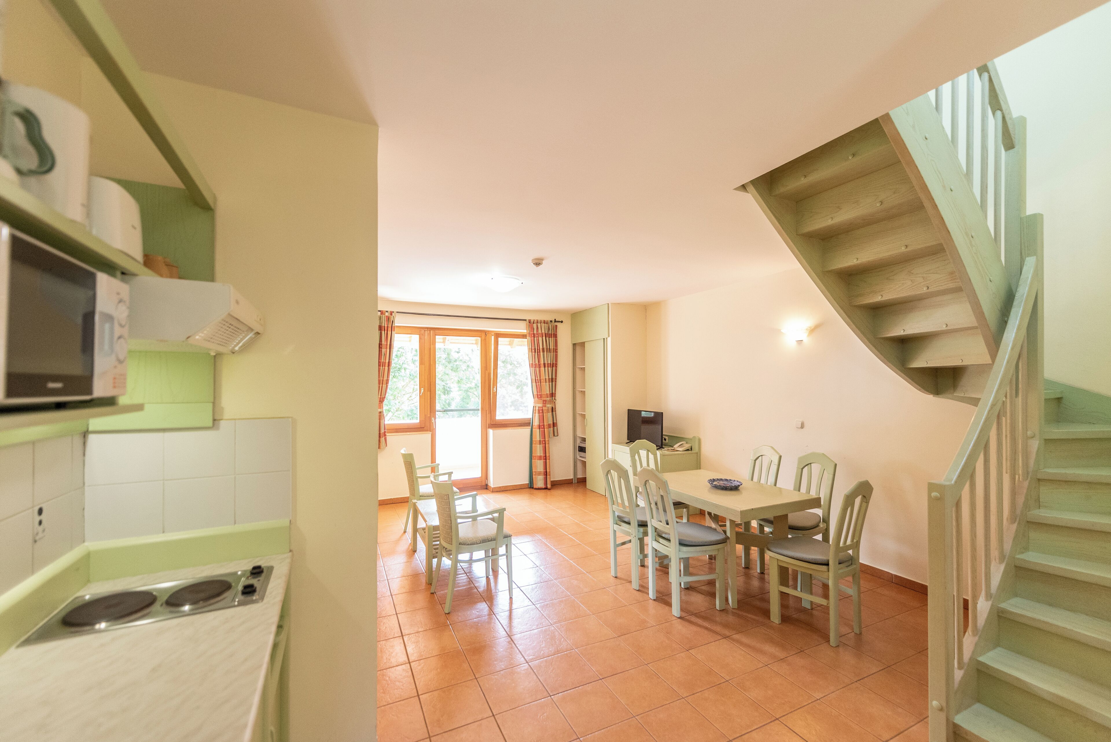 A kitchen with a stove, a dining area with a table and chairs, and a staircase.
